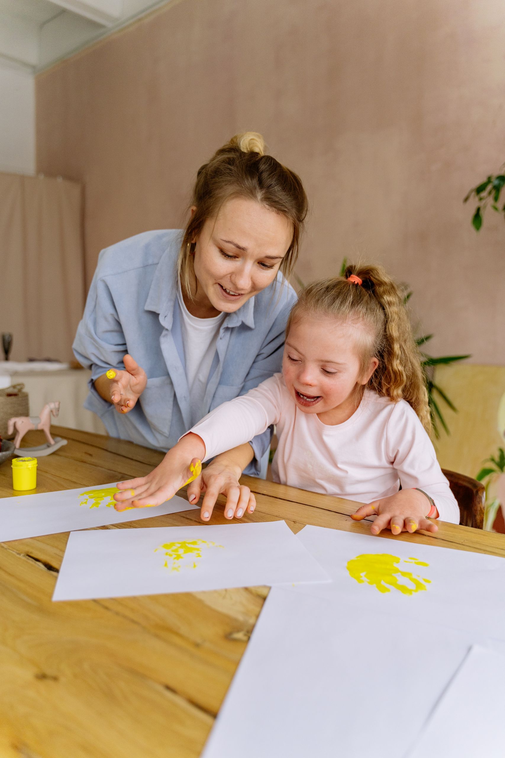 A mother and daughter joyfully painting handprints at home, fostering creativity and bonding.