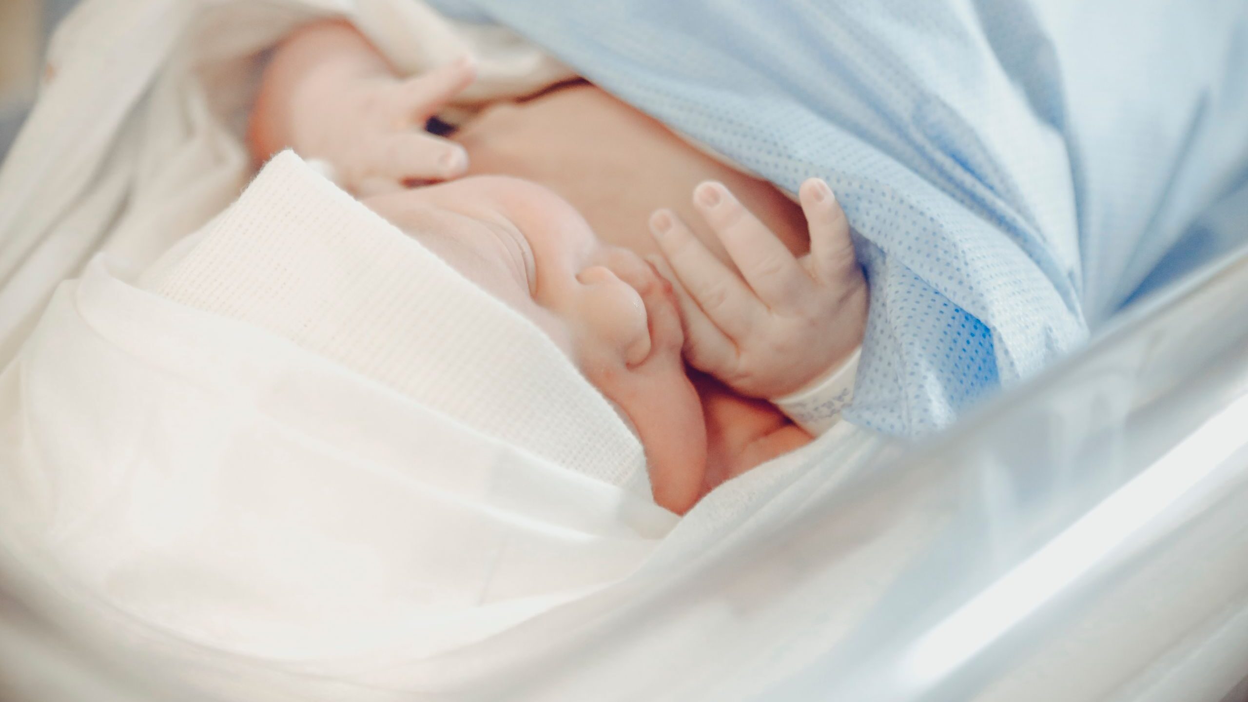 A serene newborn baby sleeping in a hospital, wrapped in a blue blanket.